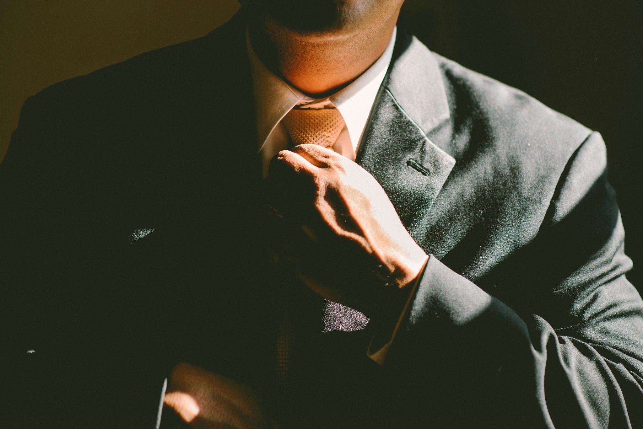 Professional salesperson adjusting tie in formal attire.